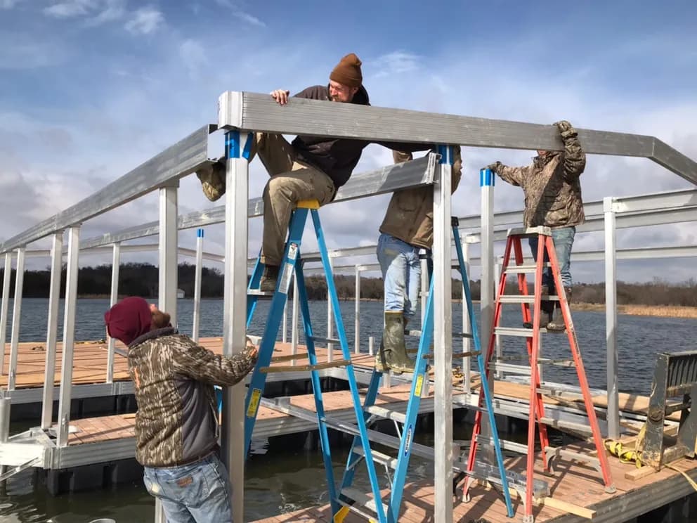 A crew assembling an aluminum dock frame out on the water.