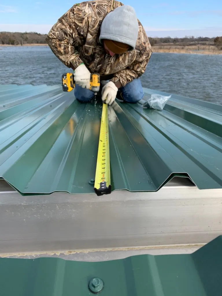 Fitting a standing-seam metal roof panel during a covered-dock install.