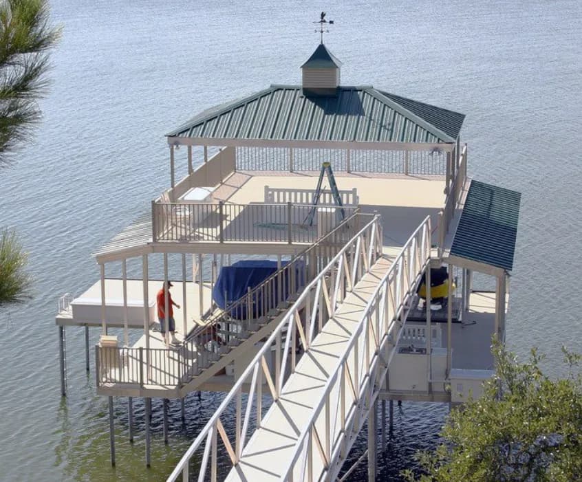 Aerial view of a two-story aluminum dock with a hip-roof cover and an open upper deck on a calm lake.