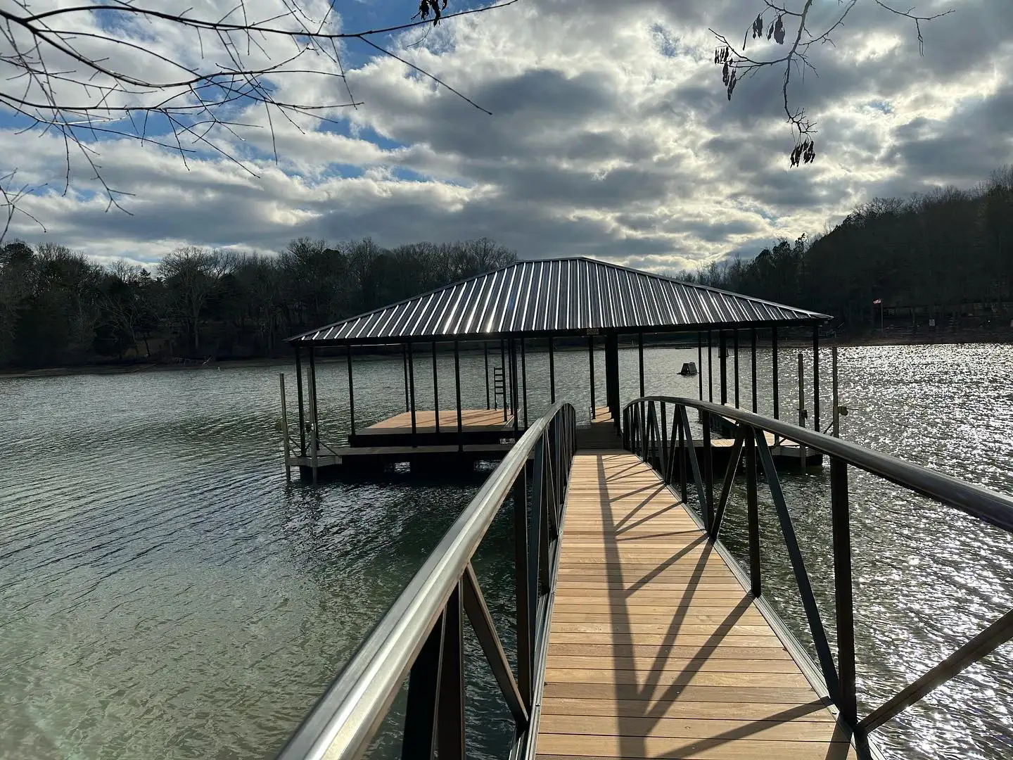 Wood-decked aluminum gangway with dark rails leading out to a covered boat dock