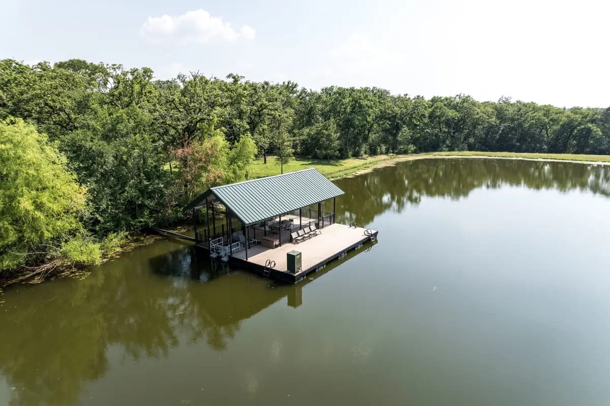 Covered floating dock with composite decking and a metal roof on a wooded Texas pond