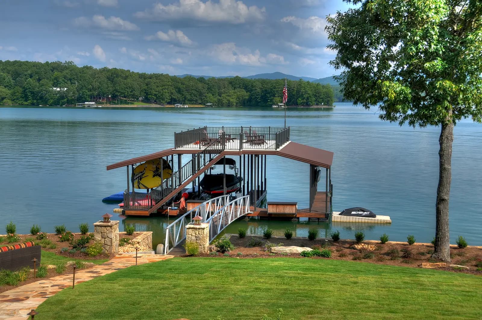 Two-story aluminum dock with a rooftop sun deck and a covered boat lift on a calm lake