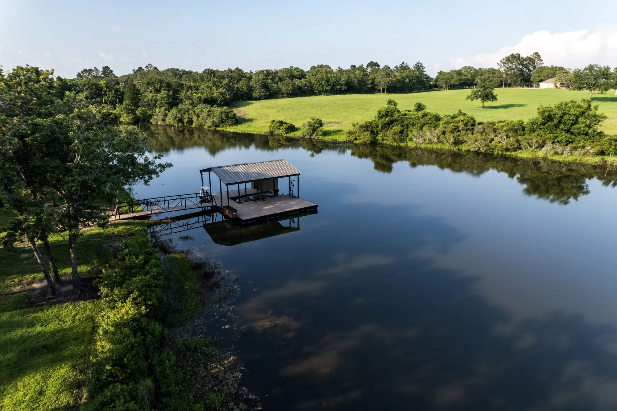 Covered aluminum floating dock and gangway on a calm Lochow Ranch lake in Texas